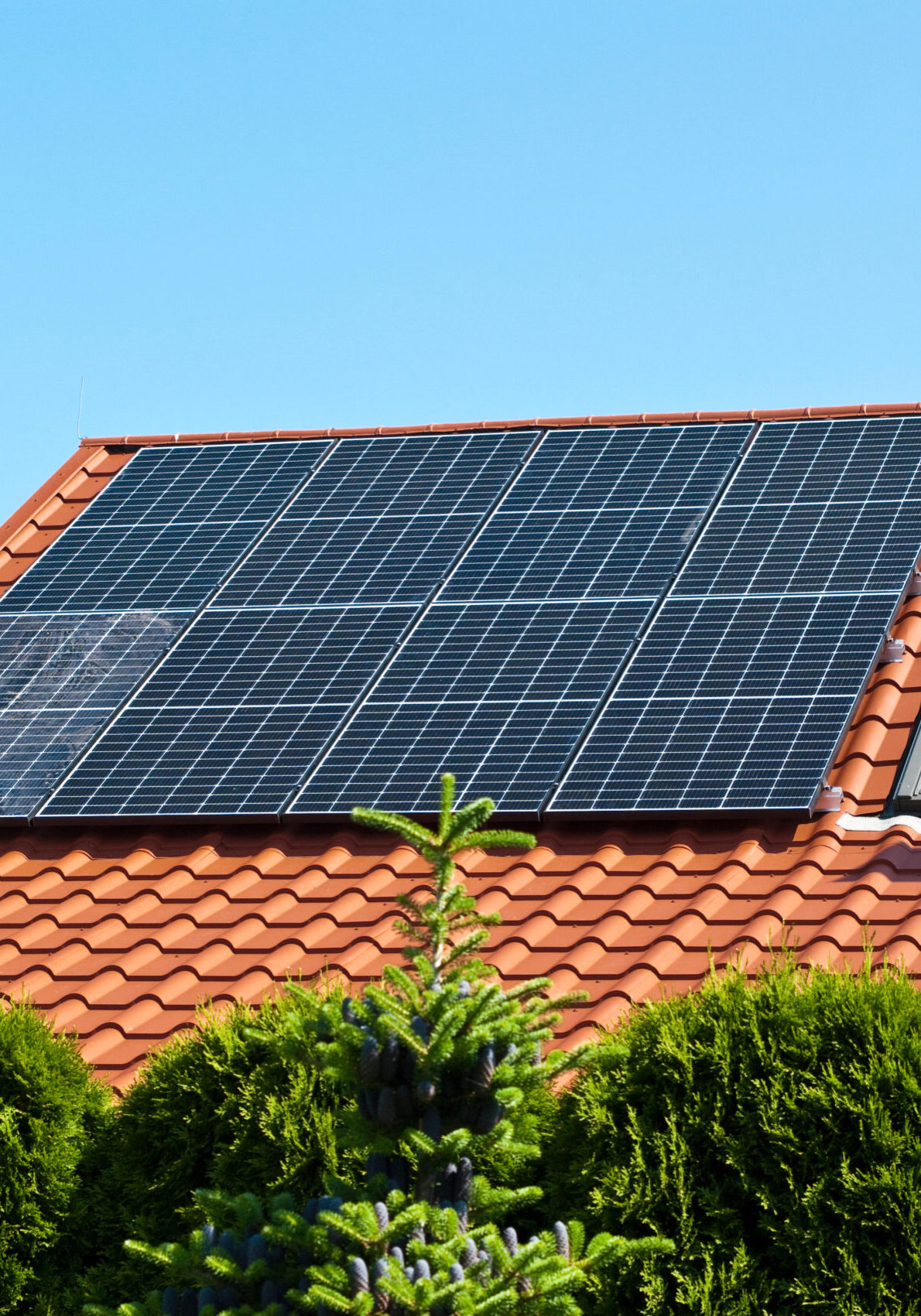 New solar panels on the red tin roof of a private house background. Renewable green energy abstract.